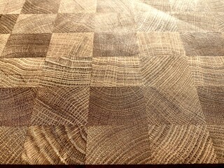 The surface of a wooden board for cooking. Close-up view of the oak cutting board in bright rays of contrasting sunlight.