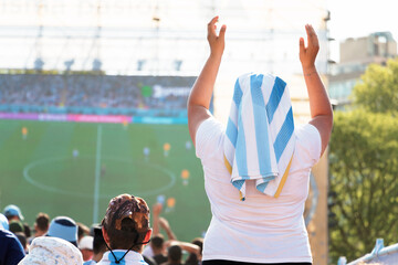 Female fan encourages the Argentine soccer team in front of a public giant screen 