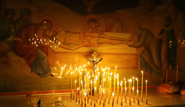 Funeral service, funeral liturgy in the Orthodox Church. Christians light candles in front of the Orthodox cross with the crucifix, the concept of Orthodox faith and religion.
