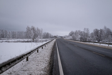 clean wet asphalt road in wintertime. Dirty snow on road sides. Long far perspective. Latvia...