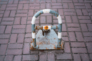 Grey and white parking lot barrier with padlock for private parking. Road limiter with a lock. Blocked. Private use. Prohibited. Barricade. Sidewalk. Pavement. Street