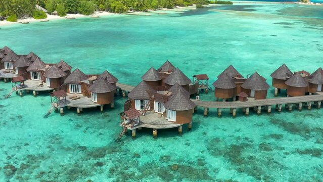 Overwater villas in tropical lagoon of Moorea Island with coral reef. Aerial drone view.