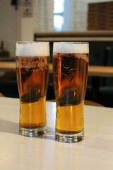 two glasses of foamy light beer in a bar, barley filtered and unfiltered beer, sports bar, beer for a football match, glasses of cool refreshing malt beer in the background of a pub, non-alcoholic