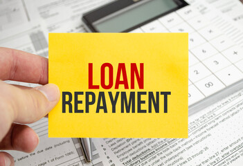 yellow paper with the words loan repayment and tax forms with calculator
