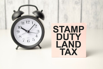 The word stamp duty land tax written on pink sticker and alarm clock