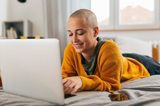 Young bald woman is doing research on her laptop