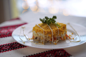 Homemade mimosa salad. Traditional Ukrainian food on the table with embroidered tablecloth.