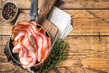 Thinly sliced German Black Forest Ham bacon in skillet. Wooden background. Top view. Copy space