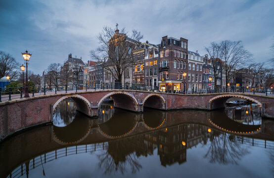 Reflection of historic canal houses and arched bridge over the Prinengracht canal in Amsterdam at dusk