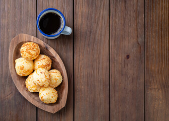Typical brazilian cheese bun in a plate with coffee over wooden table with copy space