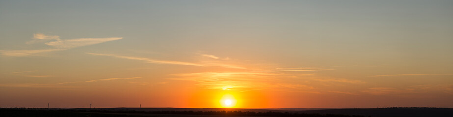 Panorama. Landscape with dawn. The sun rises through light cirrus clouds.