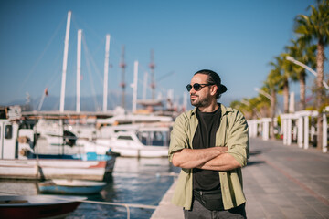 Portrait of a young contented man in the city port of sailing and motor yachts on a sunny day.