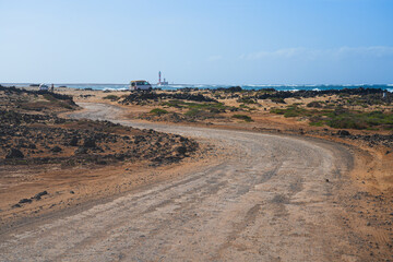 Dirt road winding following the Atlantic coast leading towards the lighthouse of El Toston on the...