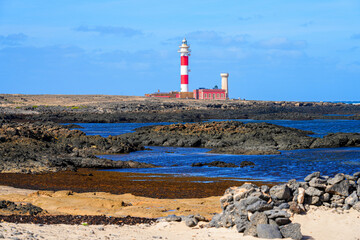Beach along the Atlantic coast with a view over the lighthouse of El Toston on the north coast of...