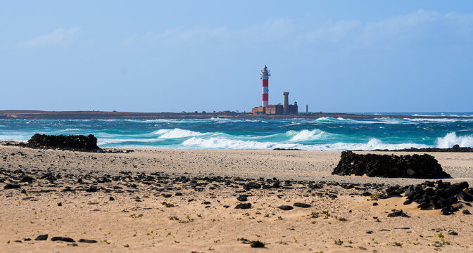 Beach along the Atlantic coast with a view over the lighthouse of El Toston on the north coast of Fuerteventura in the Canary Islands, Spain
