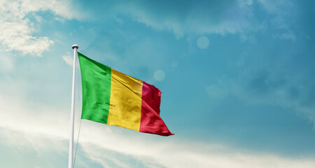 Waving Flag of Mali in Blue Sky. The symbol of the state on wavy cotton fabric.