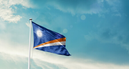 Waving Flag of Marshall Islands in Blue Sky. The symbol of the state on wavy cotton fabric.