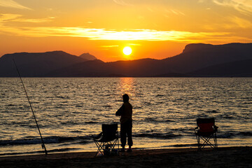 Woman fishing on Kum beach Taşucu Silifke Mersin, sunset at Tisan Dana island