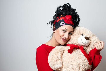 Fototapeta premium Beautiful curly young girl with bandana hairstyle holding teddy bear