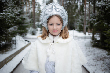 Snow Maiden , a cute young blonde in a white snow maiden costume with a kokoshnik , in the forest...