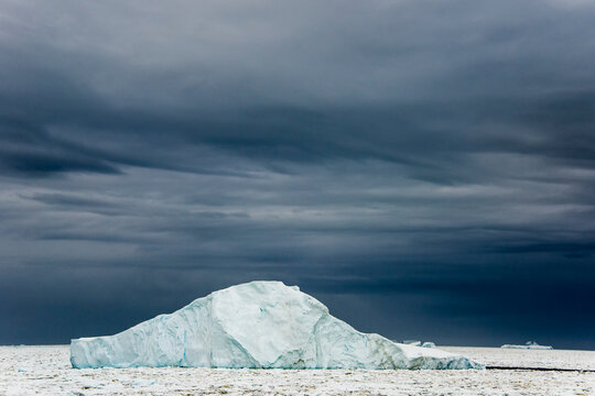 Dark clouds behind an ice floe at Penola Strait, a point far south on the Antarctic Peninsula; Antarctica