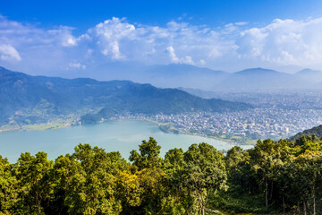 Looking across Fewa lake towards the city of Pokhara, Nepal on a sunny day, smog covering the city and surrounding areas, on a sunny autumn day; Pokhara, Kaski District, Nepal