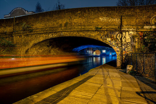Bridge crossing Regent's Canal at Shoreditch with streaking lights at night; London, England