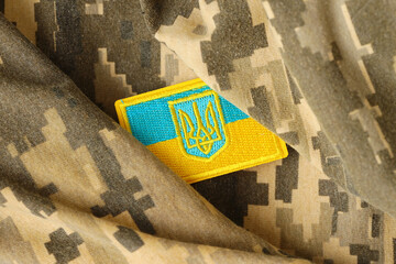 Pixeled digital military camouflage fabric with ukrainian flag and coat of arms on chevron in blue...