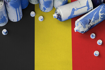 Belgium flag and few used aerosol spray cans for graffiti painting. Street art culture concept,...