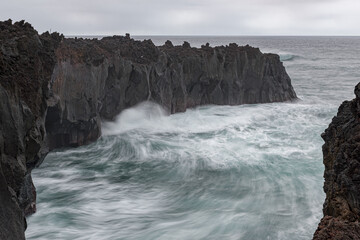 Lava cliff hit by rough sea in the area of Ponta da Ferraria on the west side of Sao Miguel island. Azores archipelago, Portugal.