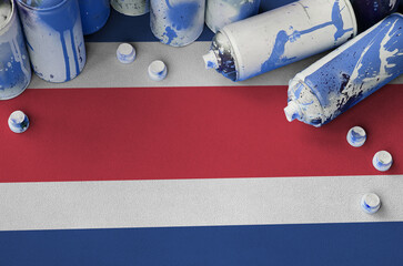 Costa Rica flag and few used aerosol spray cans for graffiti painting. Street art culture concept,...