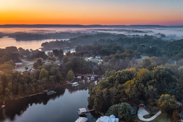 Early foggy morning aerial view of lakefront homes, boat docks and beautiful autumn colorful foliage on Tims Ford Lake in Tennessee.