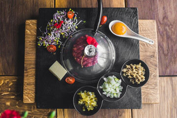Traditional Polish cuisine in modern way. Smoked beef tartar a stone plate with various ingredients. Top view. High quality photo