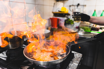 Frying pan in flames. Professional chef cooking ingredients for shrimp pasta with the use of fire. Restaurant kitchen. High quality photo