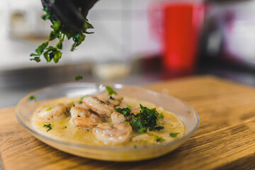 Prawns in spicy sauce with parsley. Chef preparing restaurant food. Blurred background. Eating out concept. High quality photo