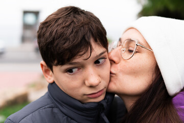 Mom kissing her teenager son on the cheek