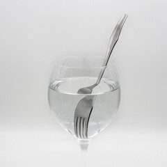 Vista de un tenedor distorsionado  dentro de una vaso lleno de agua, demostrando la refracción de la luz	