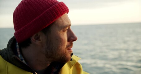 A sailor sits on a boat and smilingly looks at a lighthouse in the distance - Powered by Adobe