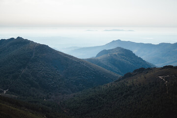 Fototapeta premium Landscape with blue layers of mountains with trees on a foggy morning in Las Villuercas, Cáceres