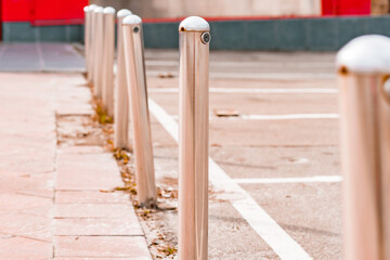 Stainless steel rounded bollard installed on the asphalt on parking near sidewalk. Security. Protection. Parking lots. Barrier. Pole. Control. Limitation. Prohibition