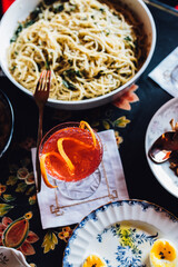 high angle view of table full of food: serving dish of pasta, soft boiled eggs, cocktail