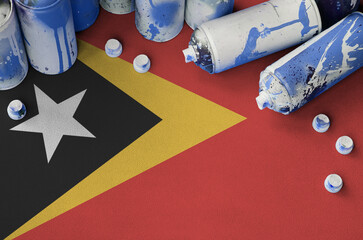 Timor Leste flag and few used aerosol spray cans for graffiti painting. Street art culture concept,...