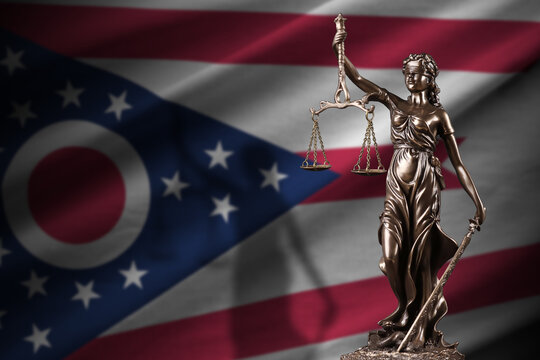 Ohio US state flag with statue of lady justice and judicial scales in dark room. Concept of judgement and punishment, background for jury topics