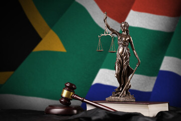South Africa flag with statue of lady justice, constitution and judge hammer on black drapery. Concept of judgement and punishment