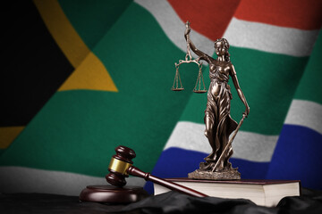 South Africa flag with statue of lady justice, constitution and judge hammer on black drapery....
