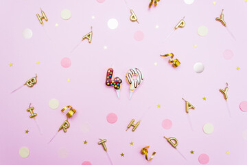 Festive candles figures in the shape of sweet donuts on a pink background surrounded by confetti. The concept of celebrating 49 years. Selective focus