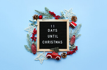 Black felt letterboard with countdown surrounded by winter decoration on blue background. 11 days until Christmas. Twenty-four day series of postcards. Selective focus