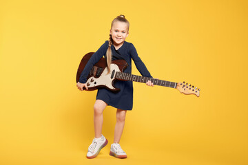 Happy girl with electric guitar on yellow background