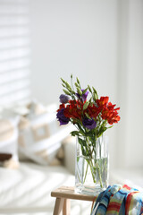 Vase with beautiful flowers on wooden table in room