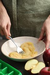 Woman making apple puree for freezing in cube tray, closeup
